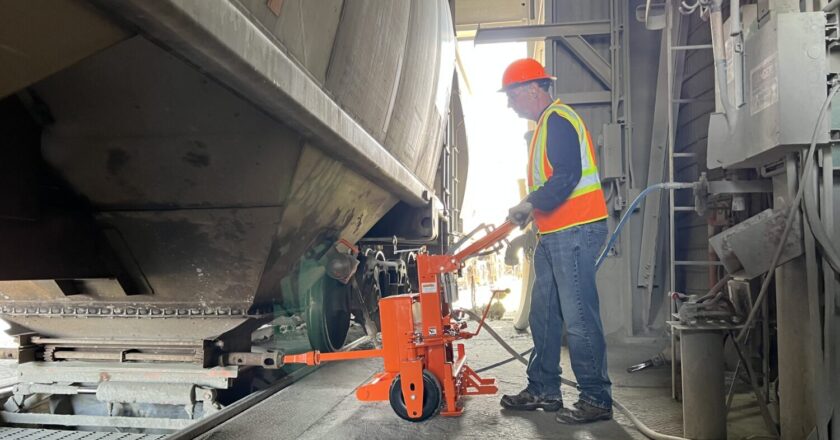 A worker inserts the bit into the capstan on a stopped hopper car to release the gate. Image: Martin Engineering
